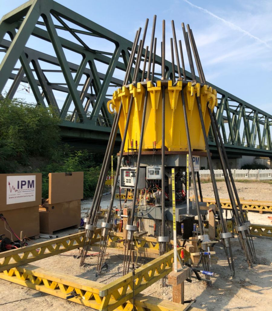Loading crown with reaction anchors in front of a truss bridge